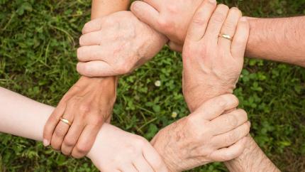 A group of hands reaches out to support each other in a circle