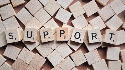A group of scrabble letters spells the word "support"