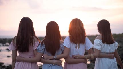 A group of women stand together showing mutual support for and with one another. Courtesy of Pexels.