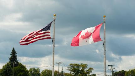 The American and Canadian flags stand next to each other. Courtesy of Pexels.