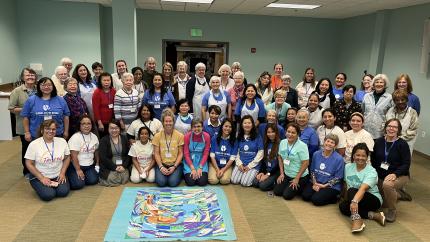 Women at a Global Coffee Break Women's Retreat gather around a shared art project