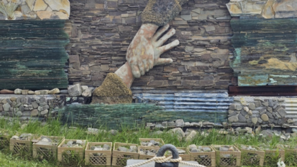 Image of a hand grabbing another hand in a memorial. Courtesy of David Odgen.
