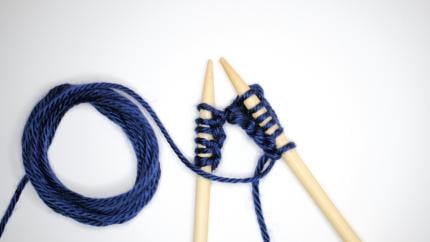 An image of blue knitting needles and yarn. Courtesy of Nik on Unsplash.