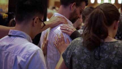 Image of a group of people praying over a ministerial candidate at Synod 2026. Courtesy of the Office of the General Secretary.