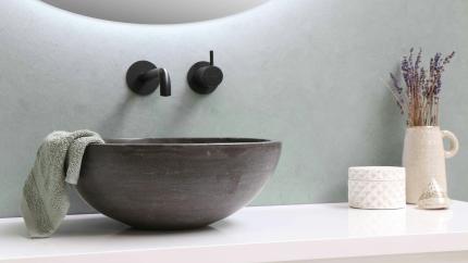 Image of a sink with faucets against a light blue wall. Courtesy of Pexels.