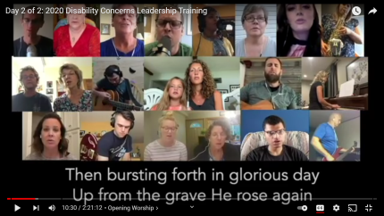 Image of many people participating in a worship song with closed captioning enabled at the bottom of the screen to read the lyrics as they are sung.