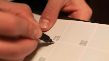 An individual writes on a calendar. Courtesy of cottonwood studios on Pexels. 