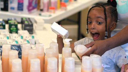 Little girl smiles in front of bottles of shampoo
