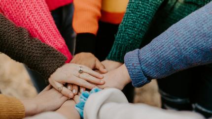 A group of multicultural hands are held together in a circle