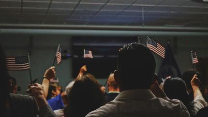 Individuals seated raising up U.S. flags