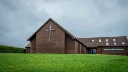 Church in a field with a cross on the building's front side