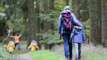 An old man walks alongside a young child while on a hike in the woods. Courtesy of Juliane Liebermann on Unsplash.