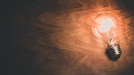 an illuminated lightbulb lays on a wood background