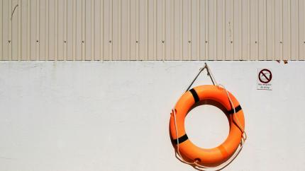 A life float is hung against a white wall. Courtesy of Unsplash.
