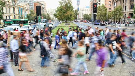 A large group of people cross a busy sidewalk in a large city. Courtesy of Unsplash.