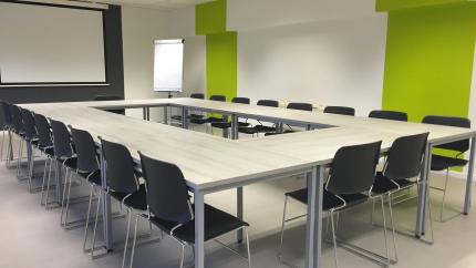 Chairs surrounding a table in a boardroom with a green background