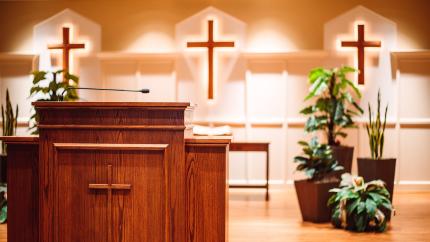 A church podium stands in front of a background with three crosses