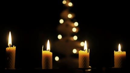 Four candles burn on a black background, reminding the reader of the four candles of a finished Advent wreath