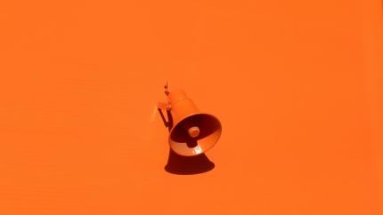 A megaphone on a deep orange background