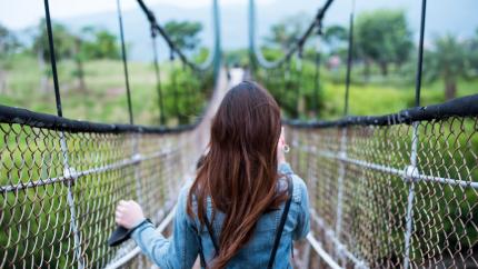 A Woman Walks Over A Rope Bridge