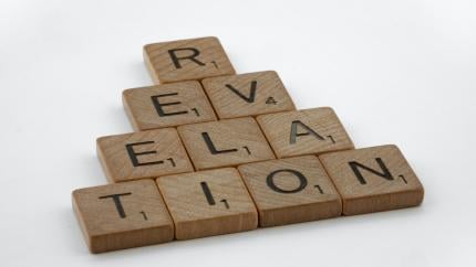 A pyramid of scrabble tiles spells the word "revelation"