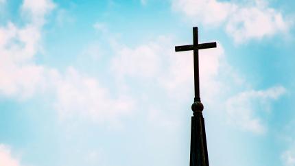 A church steeple stands against a blue sky. Courtesy of Pexels.
