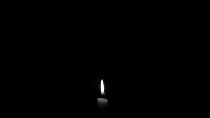 A candle shines against a black background, representing the first Sunday in Advent.