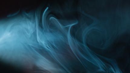 a cloud of blue smoke billows in front of a black background