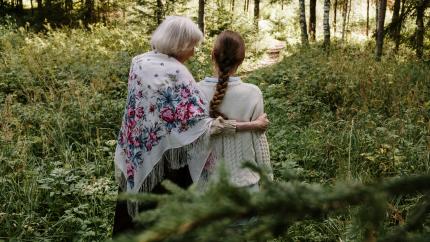 An older women embraces a young child while on a walk in the woods.