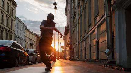 A man dances in a busy street while the sun sets in the background