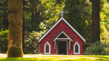 Red church building in a forested area.