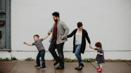 A family walks together in the rain. Courtesy of Emma Busto on Pexels.
