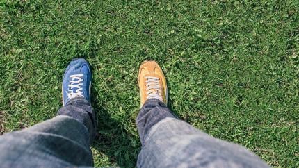 A camera view looks down at someone's two feet with different colored shoes on them