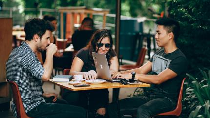 A group of young people sit at a coffee table, laughing and drinking coffee. Courtesy of Helene Lopez on Pexels.