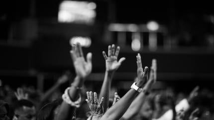 Individuals raise their arms to praise God