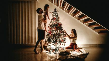 A small family works together to decorate their Christmas tree. Courtesy of Jonathan Borda on Pexels.