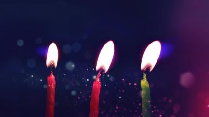 Three candles burn on a dark background