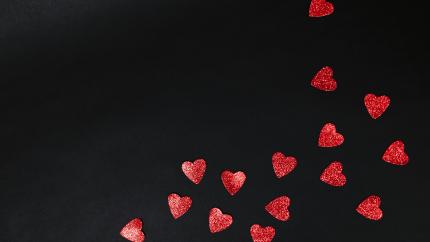 Image of a group of red hearts against a black background. Courtesy of Pexels.