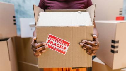 A person carries a moving box. Courtesy of Pexels.