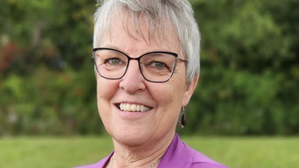 Liz Tolkamp headshot, with black glasses, a pink cardigan, and a black shirt