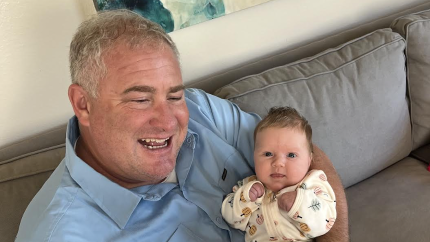 Tim Rietkirk sits reading with his baby granddaughter while he looks through his mother's book.