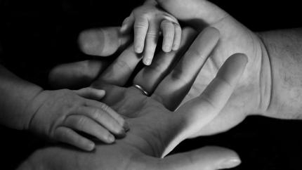 Baby hands wrapped around parents hands