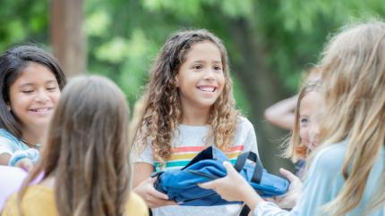 A girl smiles and hands out a pack to another girl