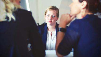 A woman looks across a table during a meeting. Photo from Tim Gouw on Pixaby.