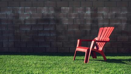 A laid-back lawn chair stands on a grassy lawn