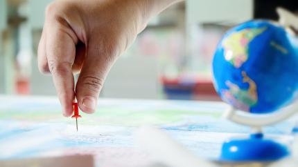 A hand placing a pin in a map