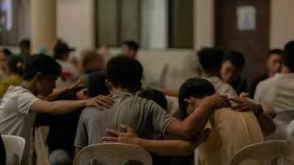 A group of boys sits in a circle, praying with each other. Courtesy of Ziph on Unsplash.