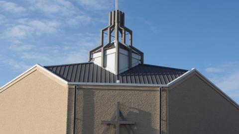 A large modern church with the CRC logo on it stands in front of a blue sky.