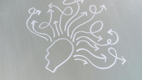 Image of the outline of a head drawn on a chalkboard, with multiple arrows drawn out from the main face. Courtesy of Pexels.