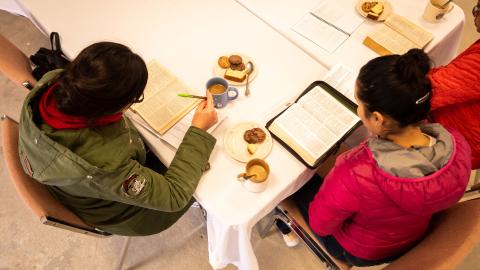 Aerial view of two women sitting at a table and studying the Bible together